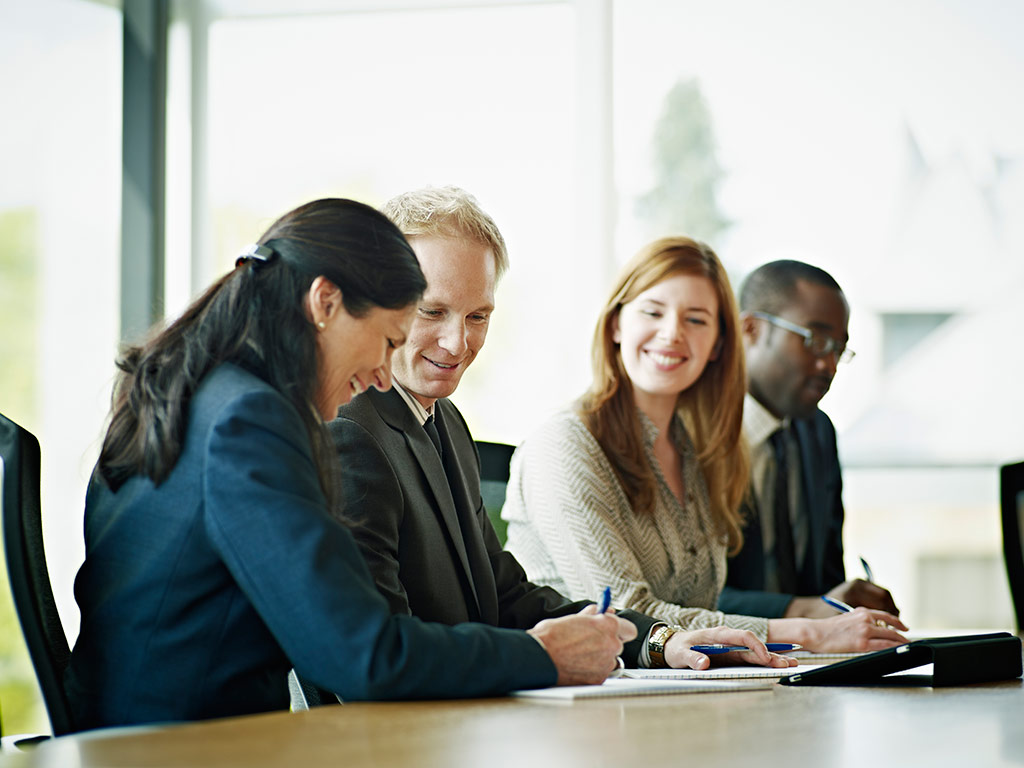 Men and women discuss meeting notes in boardroom 